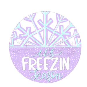 May include: Purple and white circle with a snowflake design and the text "It's Freezin Season" in white.