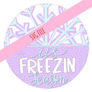 May include: A purple circle with white polka dots and the text "It's Freezin Season" in white and light blue lettering. The top half of the circle is white with a light blue and purple snowflake pattern. The text "SVG File" is written in red across the top of the circle.