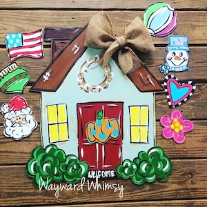 May include: A painted wooden house door hanger with a wreath, a pumpkin, and a welcome sign. The door hanger is decorated with various holiday-themed cutouts, including a snowman, a heart, a flower, a Christmas ornament, and a Santa Claus.