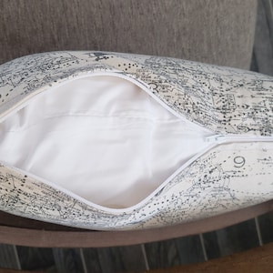 May include: A white pillow with a zipper closure. The pillow cover features a black and white map print.