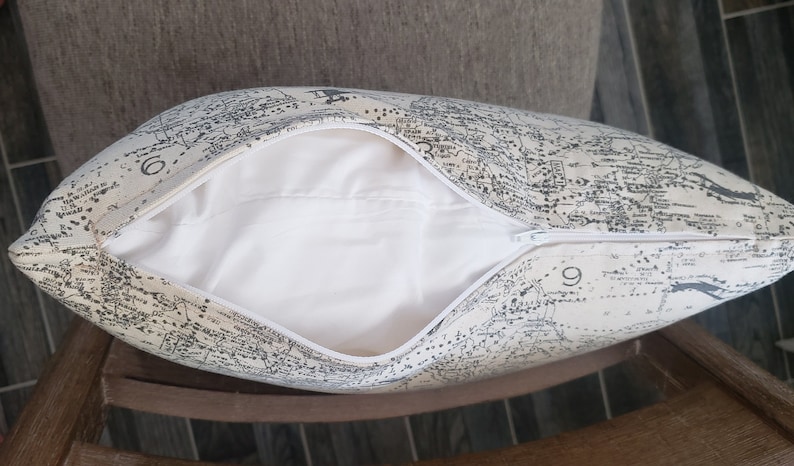 May include: A white pillow with a zipper closure. The pillow cover features a black and white map print.