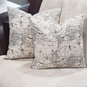 May include: Two decorative throw pillows with a black and white world map print. The pillows feature a compass design and the text "The World" in the center.
