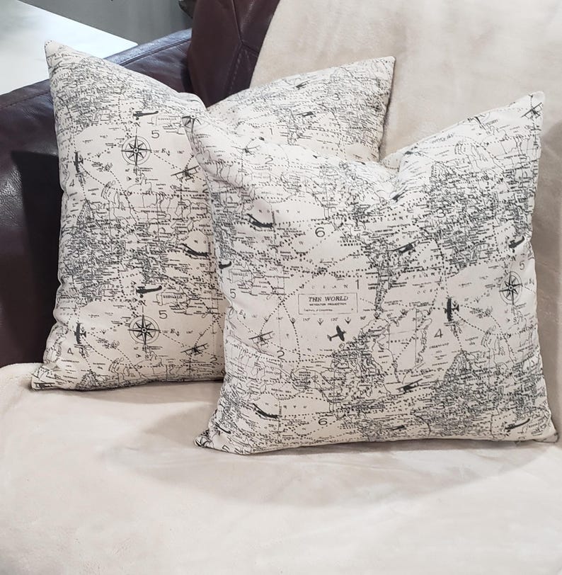 May include: Two decorative throw pillows with a black and white world map print. The pillows feature a compass design and the text "The World" in the center.