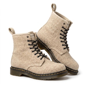 May include: A pair of beige ankle boots featuring a textured woven fabric upper, black laces, and a dark brown rubber sole with yellow stitching. Each boot has a pull tab at the heel and a small white label on the tongue with the text HEMP.