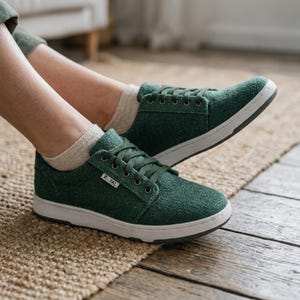 May include: Green canvas trainers with white soles and matching laces. The shoes have a low-profile design and the word "ROYAL" is printed on the side. The trainers are shown on a wooden floor.