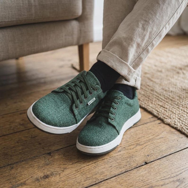 May include: Green canvas trainers with white soles and laces. The shoes have the word "RYAL" printed on the side. The trainers are shown on a wooden floor.