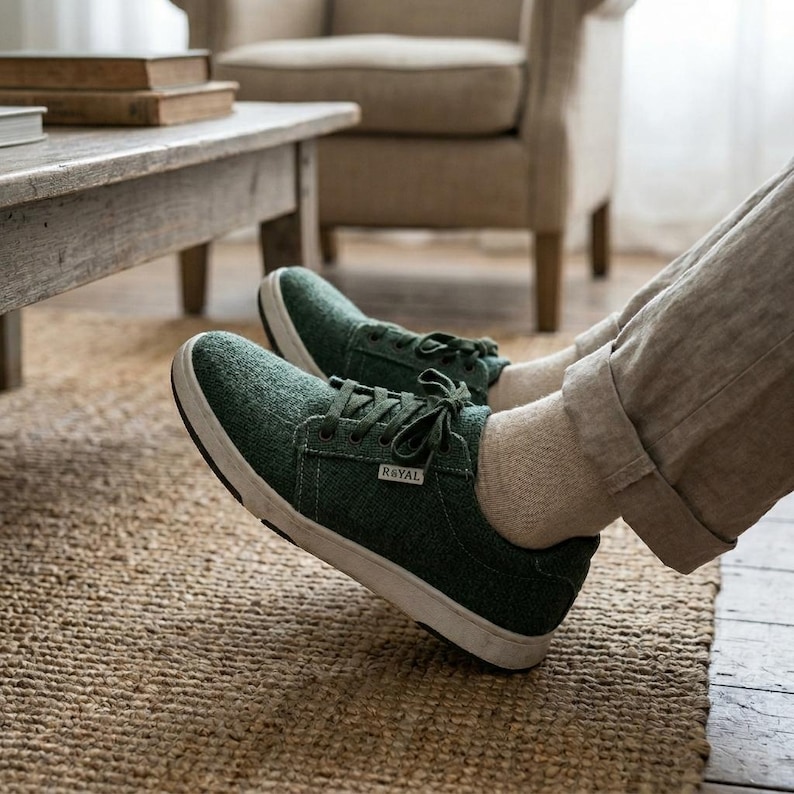 May include: Green canvas sneakers with white soles and laces. The shoes have the word "ROYAL" printed on the side. The sneakers are on a woven rug.