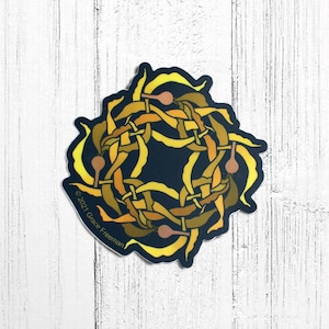 May include: A yellow and brown kelp sticker with a circular design. The sticker has a dark blue background and the text "©2021 Grace Freeman" at the bottom.