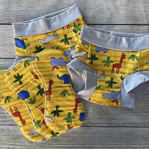 May include: Set of five yellow and blue reusable cloth pads with a safari animal print. The pads have a gray trim and are designed for use with cloth diapers.