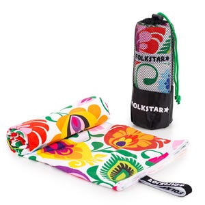 Peut inclure: Une serviette de plage enroulée et un sac de transport assorti. La serviette présente un motif floral vibrant en rouge, orange, jaune, violet et vert sur fond blanc. Le sac est noir avec un dessus en filet et le texte "FOLKSTAR".