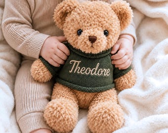 May include: A plush tan teddy bear with dark brown eyes and a dark brown nose. The bear is wearing a dark green knitted sweater with the name Theodore embroidered in a light tan script font across the center of the chest area.