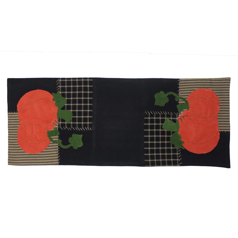 Puede incluir: Un camino de mesa rectangular con tem&aacute;tica oto&ntilde;al. El camino de mesa presenta un dise&ntilde;o de patchwork con aplicaciones de calabazas naranjas, hojas verdes y un fondo negro. El dise&ntilde;o incluye patrones a rayas y cuadros en beige y negro.