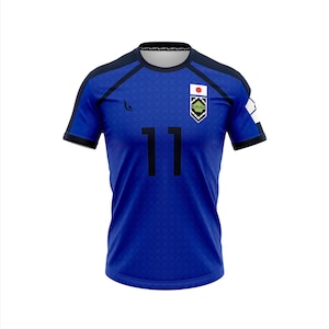May include: A blue soccer jersey with black accents, featuring the number 11 in black on the front. The jersey has a small Japanese flag and a team logo on the chest. The sleeves and shoulders are trimmed in black.
