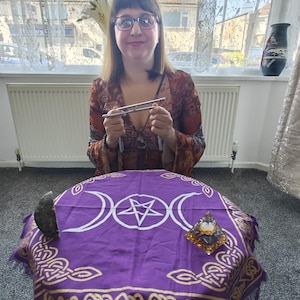 May include: A purple cloth with a pentagram, three moons, and a gold Celtic knot border. A crystal pyramid sits on the cloth.