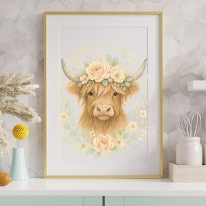 Puede incluir: Una impresión en acuarela enmarcada que presenta una vaca de las Tierras Altas con una corona floral. La obra de arte muestra una vaca marrón con pelo largo, adornada con una corona de flores amarillas y crema y hojas verdes. La impresión está en un marco dorado.