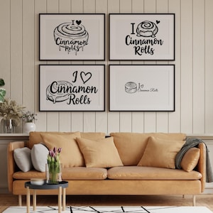 May include: Four framed art prints with black frames and white backgrounds. Each print features a black and white illustration of a cinnamon roll with the text "I Love Cinnamon Rolls". The prints are displayed above a tan sofa with pillows.