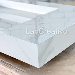 Peut inclure: Un comptoir rectangulaire blanc avec un motif marbré. Le comptoir a une finition brillante et un bord net. Le texte "LabCreativo" est visible. Il est probablement destiné à une cuisine ou une salle de bain. Mesures en cm.