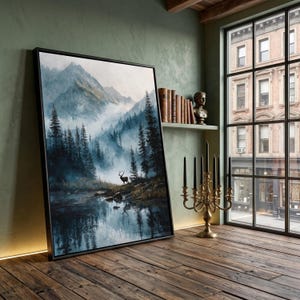 Può includere: Stampa artistica incorniciata raffigurante un paesaggio forestale con un lago e montagne. L'opera mostra un cervo vicino all'acqua, con un'atmosfera nebbiosa. La cornice è nera e la tavolozza dei colori utilizza toni freddi.