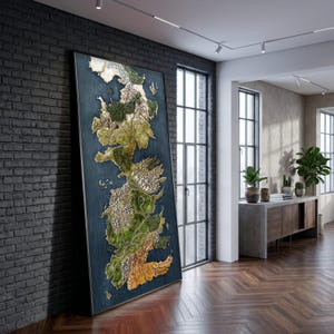 May include: A large framed map of a fantasy world, leaning against a dark brick wall. The map features detailed terrain in shades of green, brown, and gold against a blue background. The frame is black, and the room has large windows and wood flooring.