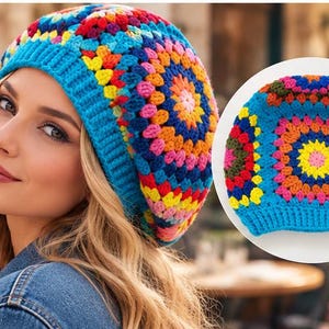 Op de afbeelding: Een gehaakte muts met een levendig granny square-patroon in de kleuren blauw, geel, roze, oranje en rood. De muts heeft een effen felblauwe geribbelde boord en een ronde kroon die is opgebouwd uit veelkleurige vierkanten van garen.