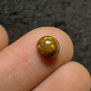 May include: A white ceramic mug with a black handle and the text "But First, Coffee" in a bold, black font. The mug is set against a blurred background, suggesting a cozy setting.