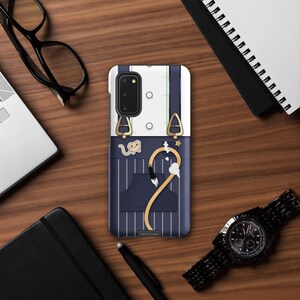 May include: A rectangular phone case featuring a graphic design of a white shirt with dark blue pinstriped trousers and gold-toned suspender clips. The design includes a small cartoon animal character and a long, curved tail illustration.