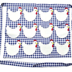 May include: A blue and white gingham apron featuring twelve white chicken appliqu&eacute;s arranged in three rows of four. Each chicken has a red comb and wattle with a yellow beak. The apron includes long fabric ties along the top and bottom edges.