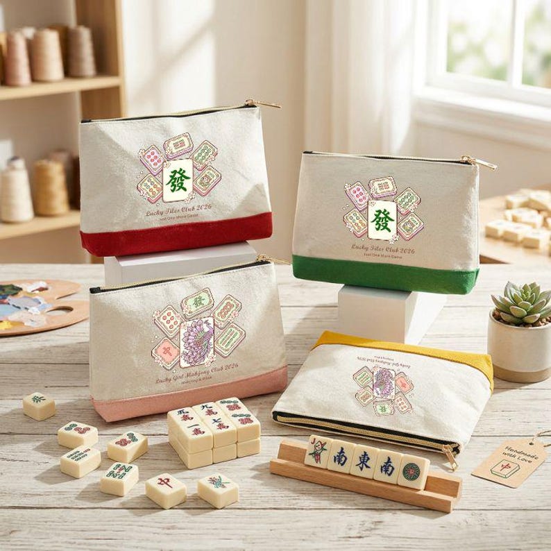 May include: Four canvas zipper pouches with colorful bottoms, featuring a Mahjong tile design and the text "Lucky Girl Mahjong Club 2026". Mahjong tiles and a wooden rack are also visible.