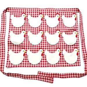 May include: A red and white gingham apron featuring twelve white chicken appliqu&eacute;s arranged in three rows of four. Each chicken has a yellow beak and a red comb. The apron includes long fabric ties at the top and bottom for securing around the waist.