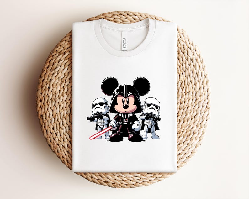 Pu&ograve; includere: T-shirt bianco con un'illustrazione di Mickey Mouse vestito da Darth Vader, affiancato da due Stormtrooper. Mickey Mouse tiene una spada laser rossa. Il disegno &egrave; centrato sulla maglietta.
