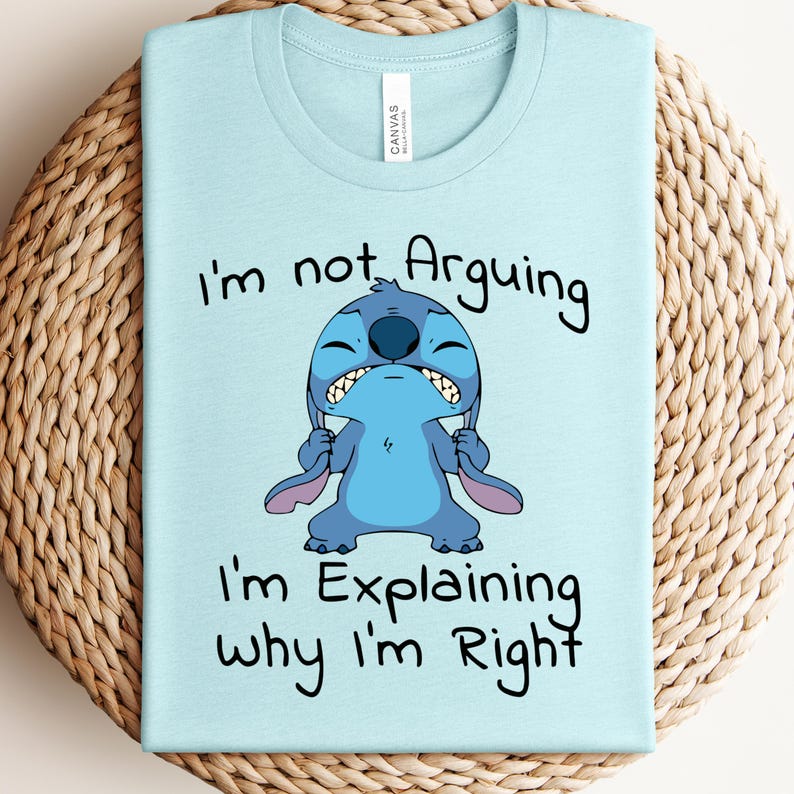 May include: Light blue t-shirt featuring a cartoon character with the text "I'm not Arguing, I'm Explaining why I'm Right". The graphic shows a blue alien-like creature with a grumpy expression.