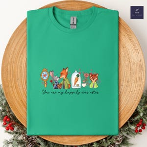 May include: A green t-shirt featuring a cartoon design with characters from Zootopia. The design includes a mirror, a bunny, a fox, a carrot in a glass dome, a rose, and the text "You are my happily ever after."