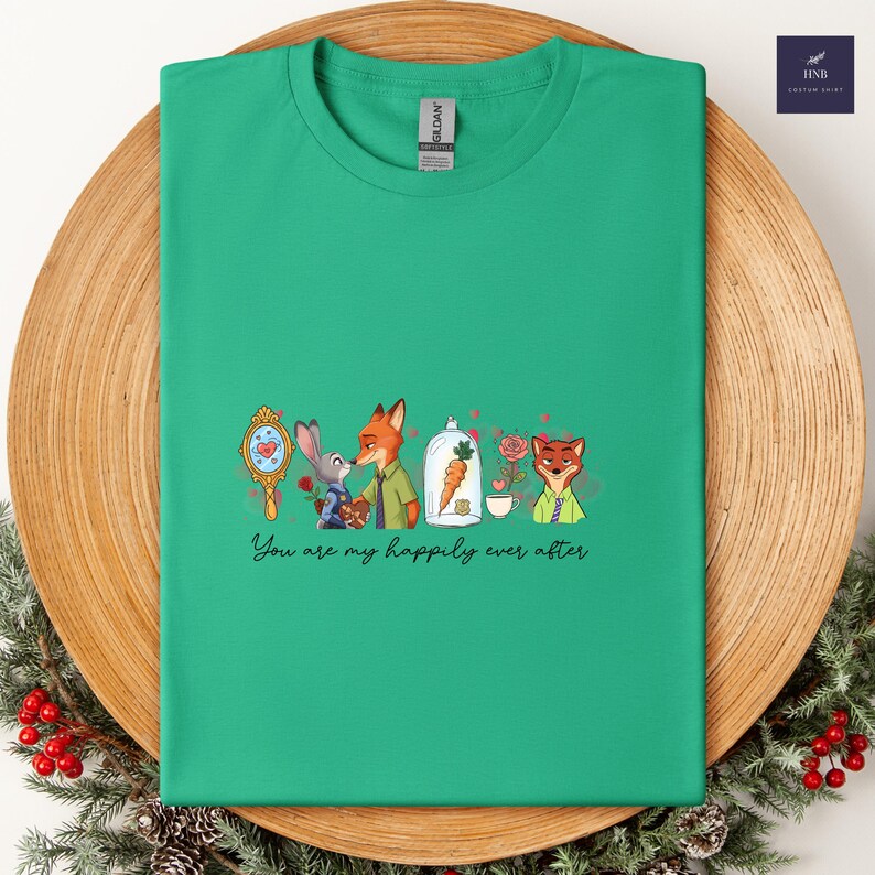 May include: A green t-shirt featuring a cartoon design with characters from Zootopia. The design includes a mirror, a bunny, a fox, a carrot in a glass dome, a rose, and the text "You are my happily ever after."