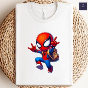 Puede incluir: Camiseta blanca con un dise&ntilde;o de dibujos animados de Spider-Man. El personaje lleva su traje rojo y azul, con una mochila. La camiseta tiene cuello redondo y la marca "Canvas" est&aacute; impresa en la camiseta. Fondo tejido.
