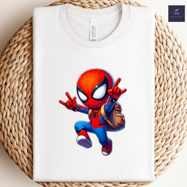 Puede incluir: Camiseta blanca con un dise&ntilde;o de dibujos animados de Spider-Man. El personaje lleva su traje rojo y azul, con una mochila. La camiseta tiene cuello redondo y la marca "Canvas" est&aacute; impresa en la camiseta. Fondo tejido.