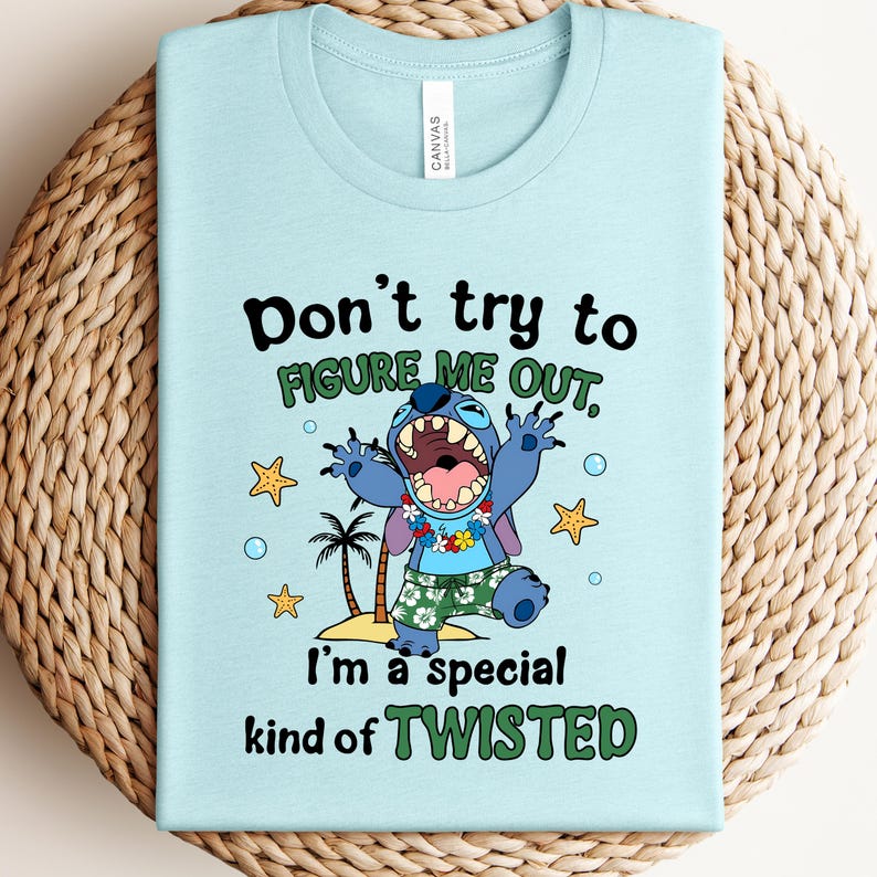 May include: Light blue t-shirt featuring a cartoon character with the text "Don't try to figure me out, I'm a special kind of twisted." The character is blue with large ears, wearing floral shorts and a lei.