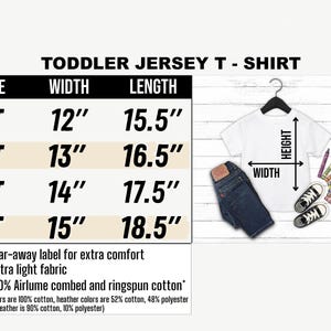 May include: A white toddler jersey t-shirt with size and measurement details. The shirt is displayed with a pair of blue jeans, black sneakers, and crayons. Measurements are provided in inches: width from 12" to 15", length from 15.5" to 18.5".
