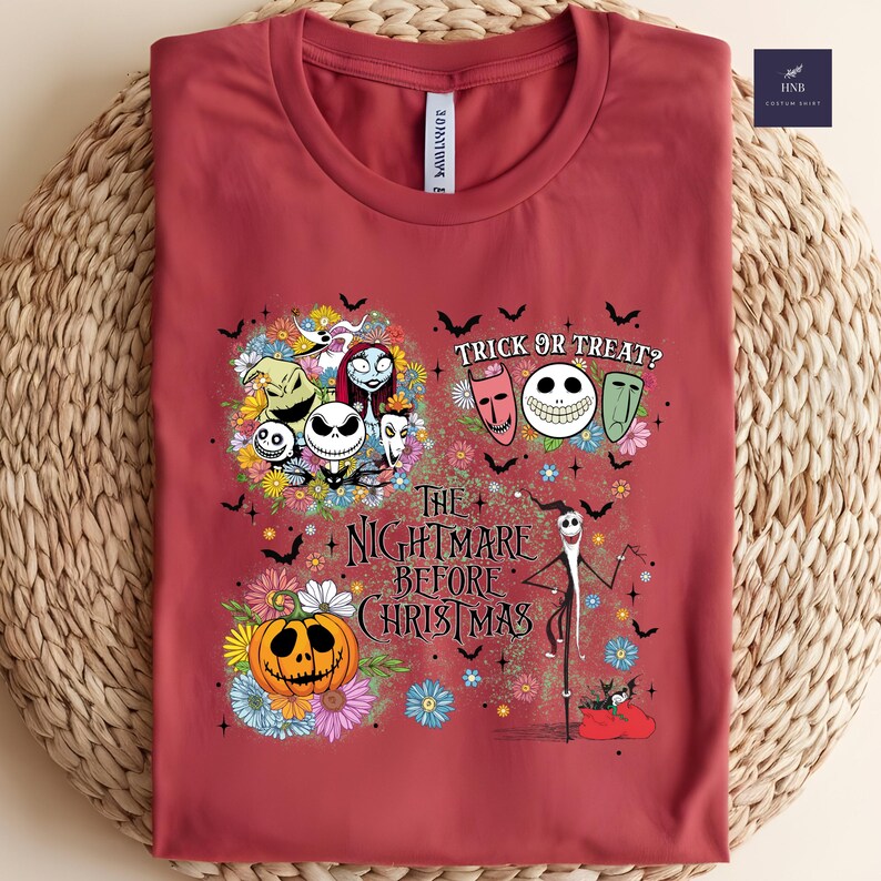 May include: A maroon t-shirt featuring a colorful graphic from "The Nightmare Before Christmas." The design includes Jack Skellington, Sally, Zero, and other characters, along with the text "Trick or Treat?" and "The Nightmare Before Christmas."