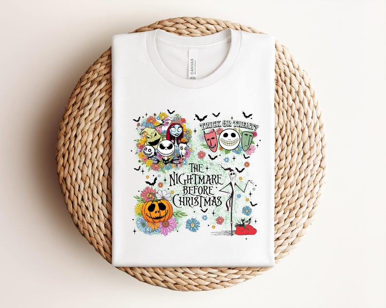 May include: White t-shirt featuring a colorful graphic from "The Nightmare Before Christmas." The design includes Jack Skellington, Sally, Zero, and other characters, along with the text "Trick or Treat" and "The Nightmare Before Christmas."