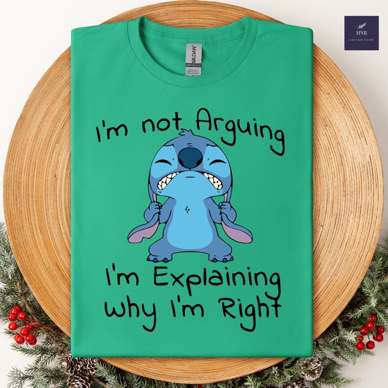 May include: A green t-shirt featuring a cartoon character with the text "I'm not Arguing, I'm Explaining why I'm Right." The character is blue with large ears and a grumpy expression. The shirt is a Gildan brand.