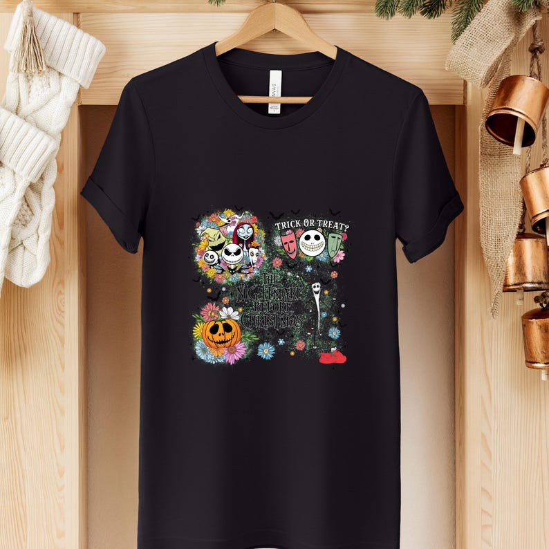 May include: Black t-shirt featuring a colorful graphic design with characters and text from "The Nightmare Before Christmas." The design includes Jack Skellington, Sally, and other characters, with the words "Trick or Treat?" and "This is Halloween."