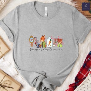 May include: A heather gray t-shirt featuring a cartoon design with characters from Zootopia. The design includes a mirror, bunny, fox, carrot, and the text "You are my happily ever after."