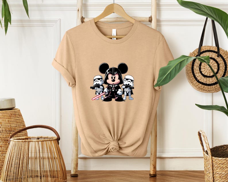 Pu&ograve; includere: T-shirt color cachi con grafica a cartoni animati di Topolino vestito da Darth Vader, affiancato da due Stormtrooper. Il design include una spada laser rossa ed &egrave; centrato sul davanti della maglietta.