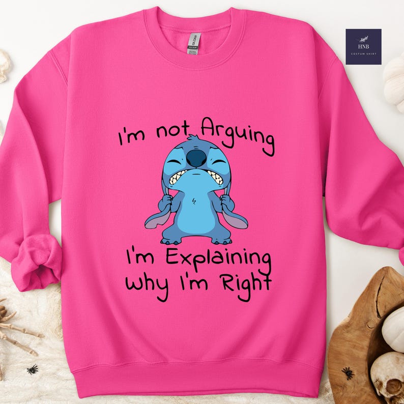 May include: A hot pink sweatshirt featuring a cartoon image of Stitch with the text "I'm not Arguing, I'm Explaining why I'm Right". The blue Stitch character has an angry expression. The sweatshirt is a Gildan brand.