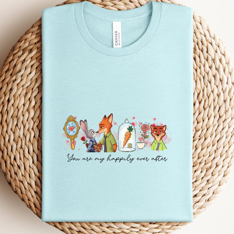 May include: A light blue t-shirt featuring a cartoon design with characters from Zootopia. The design includes a mirror, bunny, fox, carrot, and roses. The text "You are my happily ever after" is written below the design.