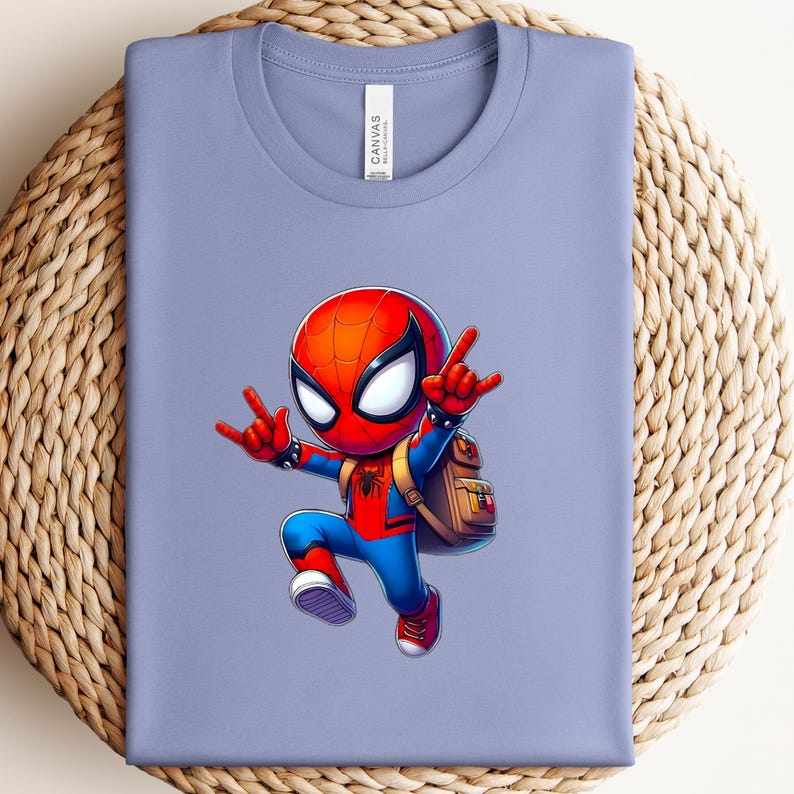 Puede incluir: Camiseta lila claro con un dise&ntilde;o de dibujos animados de Spider-Man. El personaje, con traje y m&aacute;scara rojos y azules, hace un gesto con la mano y lleva una mochila. La camiseta tiene una etiqueta en el cuello.