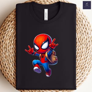 Puede incluir: Camiseta negra con un dise&ntilde;o de Spider-Man de dibujos animados, en una pose din&aacute;mica, con una mochila. El personaje est&aacute; representado en rojo, azul y negro. La camiseta tiene una etiqueta "CANVAS".