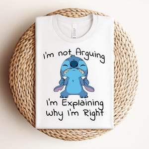 May include: White t-shirt featuring a cartoon image of Stitch with the text "I'm not Arguing, I'm Explaining Why I'm Right." The design includes a blue Stitch character with a grumpy expression.