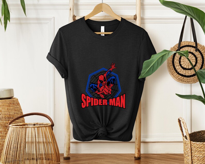 May include: Black t-shirt featuring a Spider-Man graphic. The design includes a red and blue Spider-Man figure within a blue web-like frame, with the words "SPIDER MAN" in red below.
