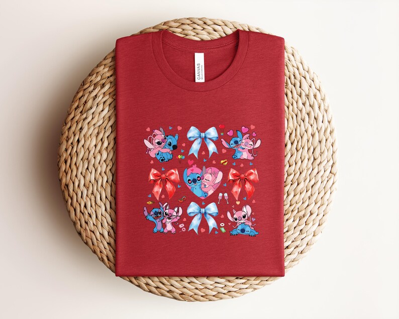 May include: A red t-shirt featuring a graphic design of the characters Stitch and Angel, with bows and hearts. The design includes the word "Canvas" on the tag.